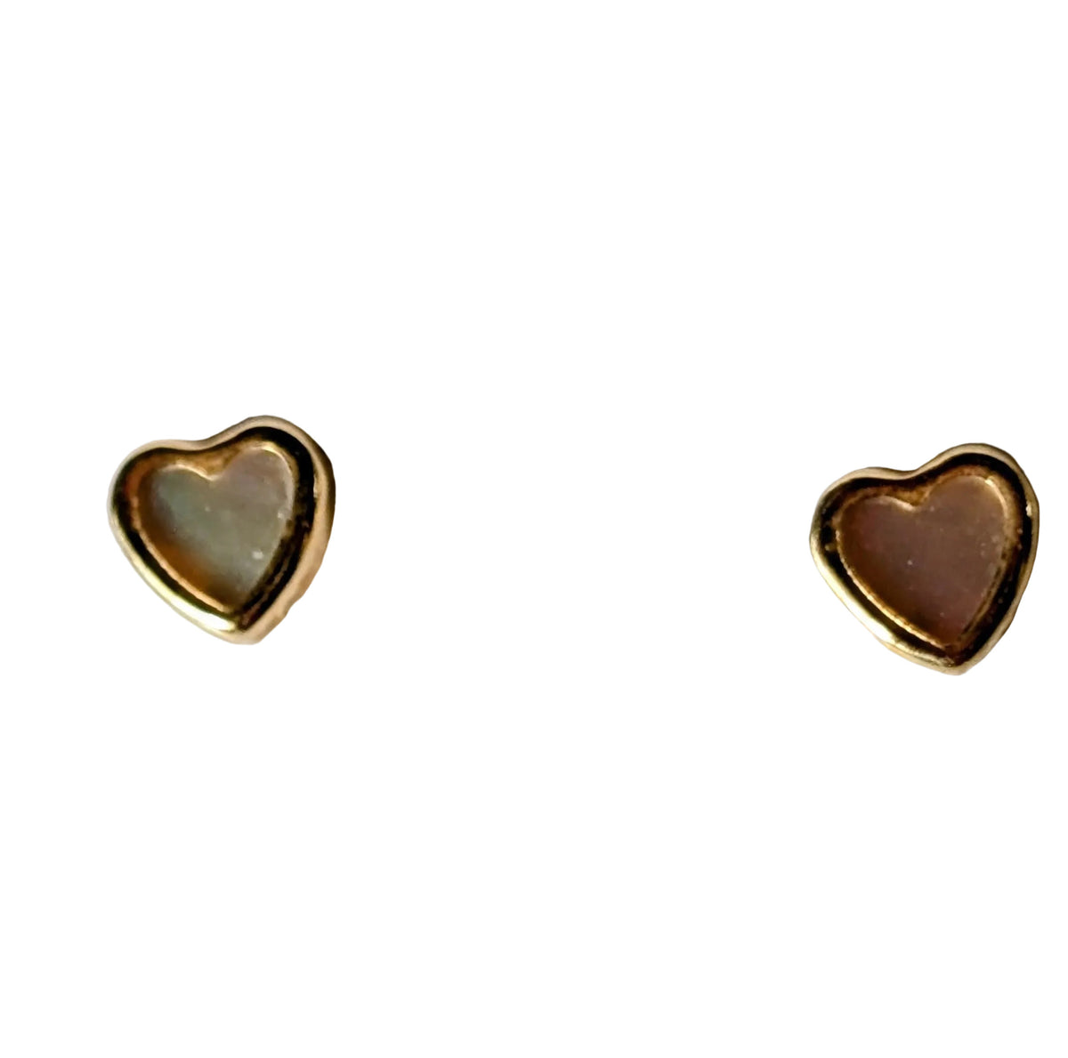 A pair of small heart-shaped stud earrings with gold borders and pale pinkish-beige centers, displayed on a textured white surface.