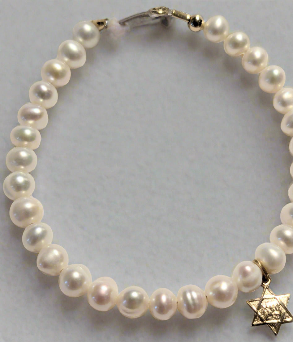 A white bracelet made of freshwater pearls and 14 KT gold, featuring a Star of David charm with the Hebrew word Zion.