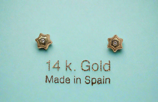 A pair of 14 KT gold screw back earrings featuring a Star of David design with a beaded trim and a sparkling central stone, displayed on a white background with '14 k. Gold Made in Spain' printed below.