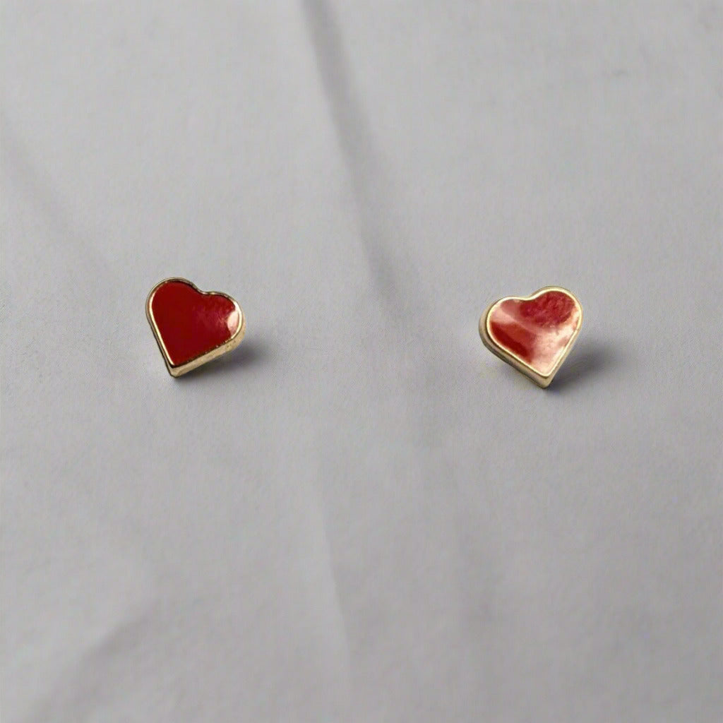 A pair of 14 KT gold children's heart-shaped screw back earrings with red enamel, displayed in a white box.