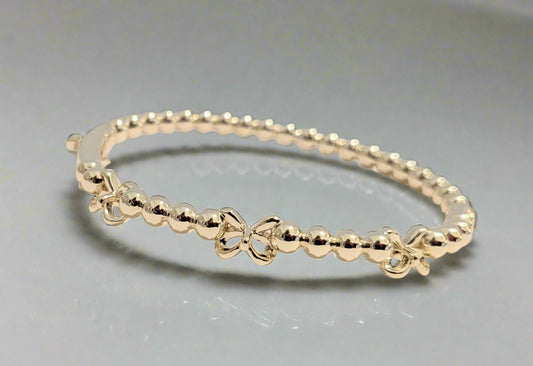 Gold bracelet on a light beige surface with a soft gray background
