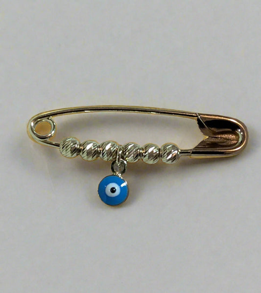 Gold safety pin with a blue evil eye charm on a light blue background