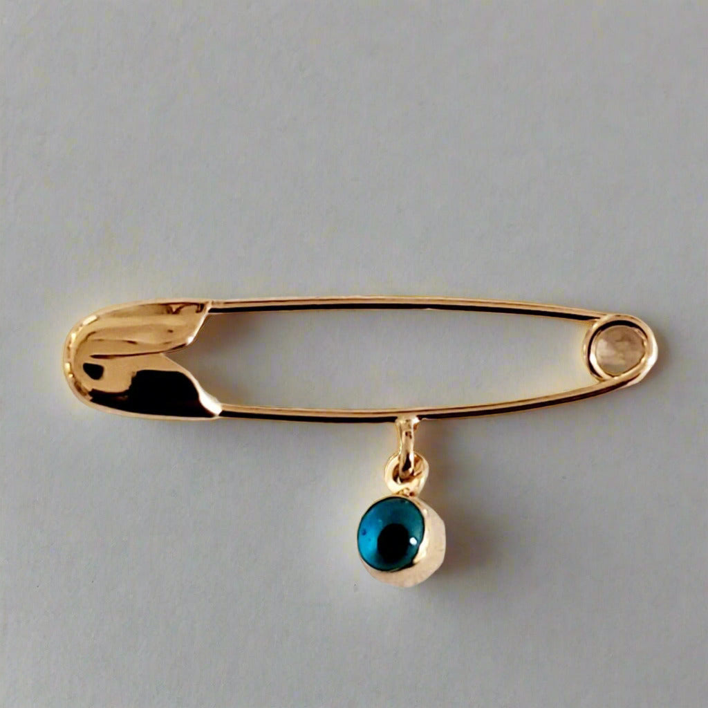 Safety pin with glass eye charm