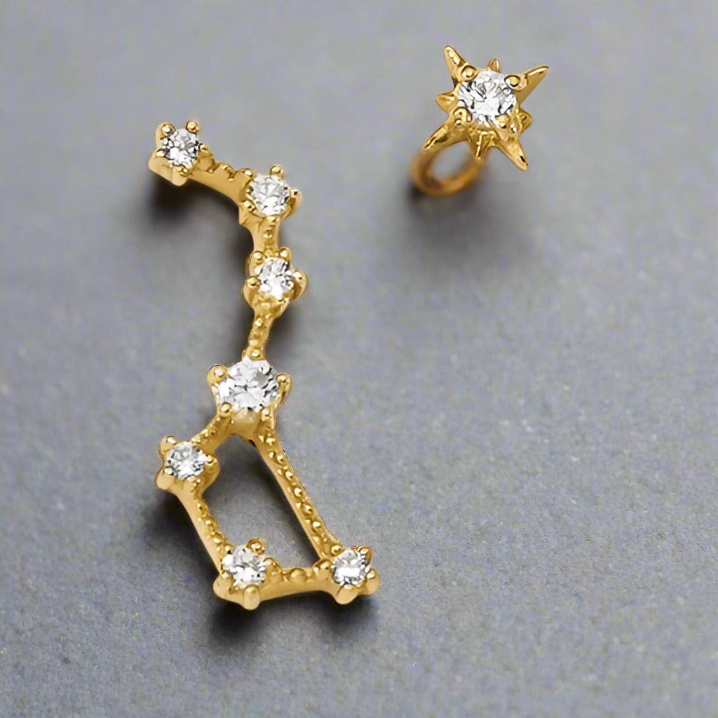 Gold earring with diamond-like stones on a gray background