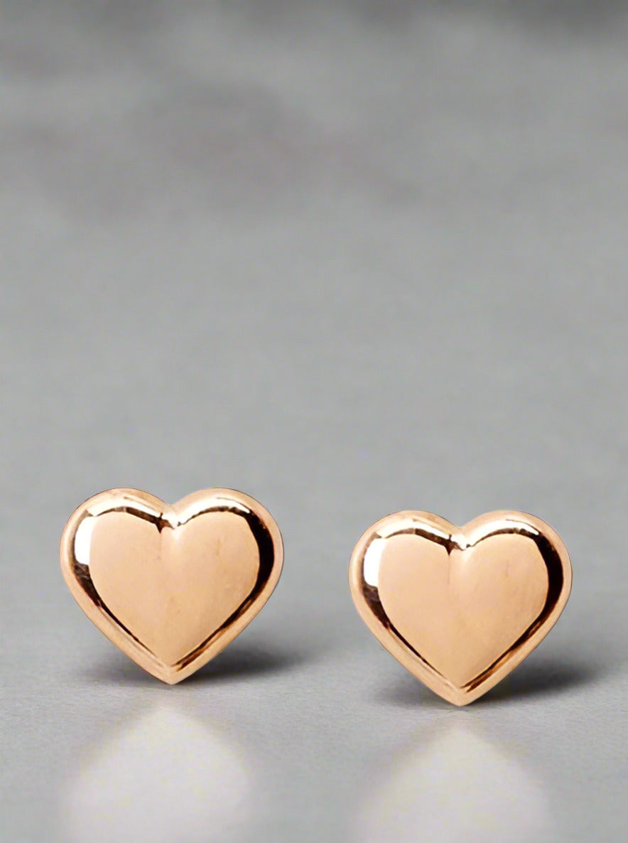 A pair of rose gold heart-shaped clutch back earrings for children.
