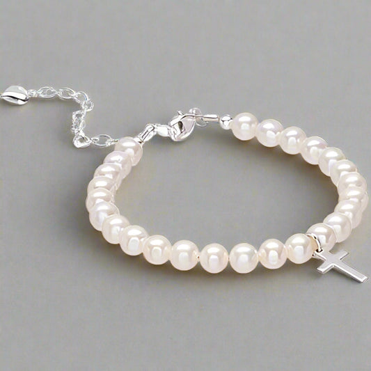 A pearl bracelet with a sterling silver cross and a lobster clasp, displayed on a chain.
