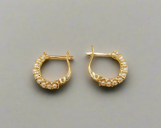 A pair of 14 KT gold hoop earrings with seed pearls and locking backs, displayed against a white background.