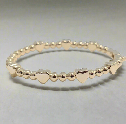 Gold beaded bracelet with heart-shaped beads on a light background