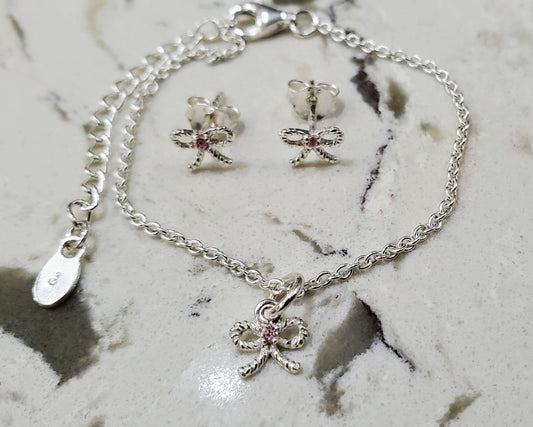 Baby or child's sterling bow bracelet and earrings set with pink CZ stones in the center.  Antiqued finish. Bows are twisted shape. Bracelet finished with lobster clasp and 2 inch extender.